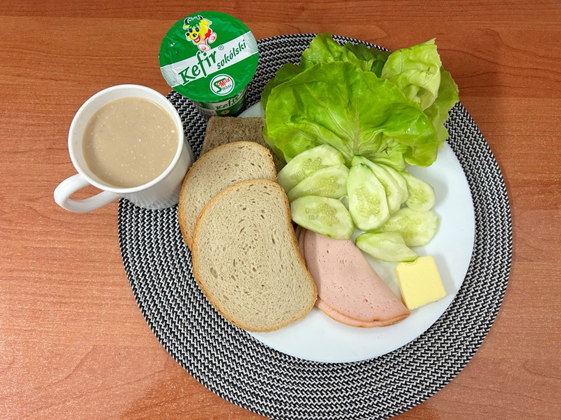 Na zdjęciu: Kefir 2%, Kawa zbożowa z mlekiem, Chleb mieszany pszenno-żytni, Chleb Graham,Masło extra 82%, Filet zapiekany, Ogórek świeży, Sałata zielona